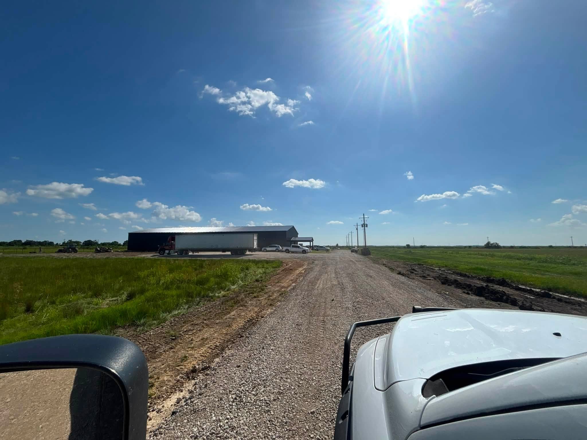 Extended gravel driveway running out to a metal barn