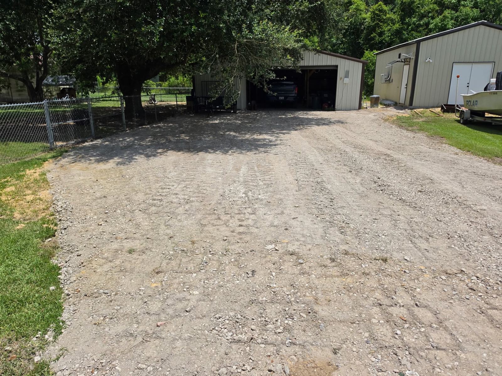Graded gravel driveway and parking area leading to a shop building in Winnie, TX